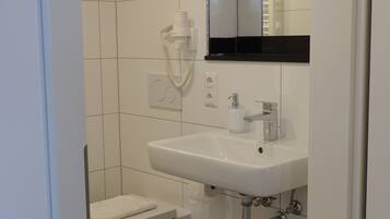 A small, clean bathroom with a white sink, toilet, and a mirror above the sink.
