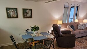 A dining area with a glass table and chairs, a brown sofa, and a potted plant. - Beach Front Condo PCB! Spring/Fall and Winter Discount Rates Available Now!! (Panama City Beach)
