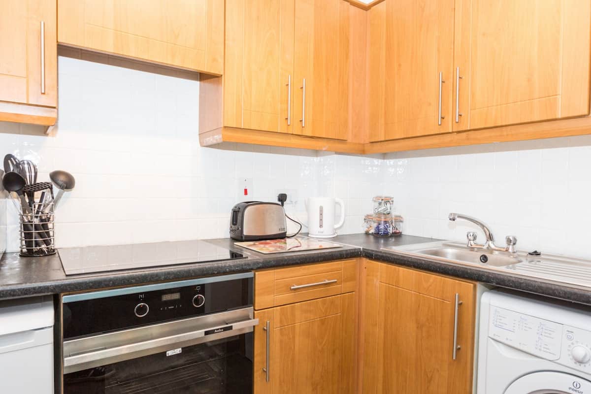 A kitchen with wooden cabinets, a microwave, toaster, sink, and dishwasher.