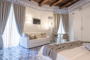 Un dormitorio con una cama, un sofá blanco, una mesita con sillas y un armario.