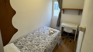 A small, single-bed room with a ceiling fan, a desk, and a window with curtains. - Residencia Rosales (Madrid)