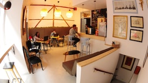 A café with tables and chairs, a bar area, and a staircase. - Residencia Rosales (Madrid)