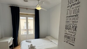 A hotel room with two beds, a desk, and a ceiling fan. - Residencia Rosales (Madrid)