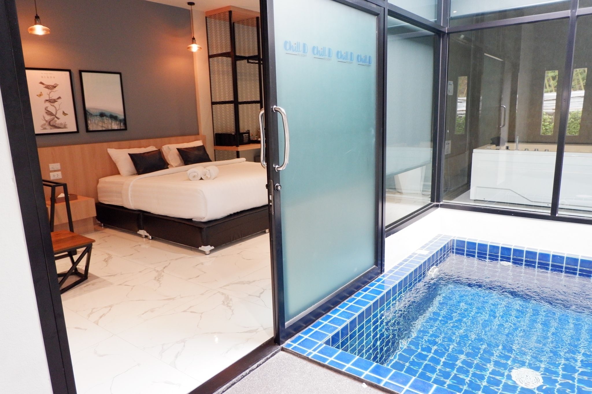 Una habitación de hotel moderna con una cama, un vidrio que da a una piscina y vistas al exterior.