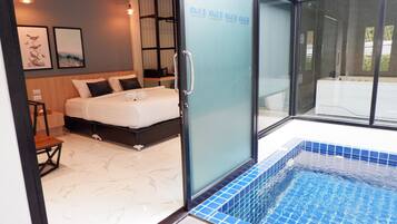 Una habitación de hotel moderna con una cama, un vidrio que da a una piscina y vistas al exterior.