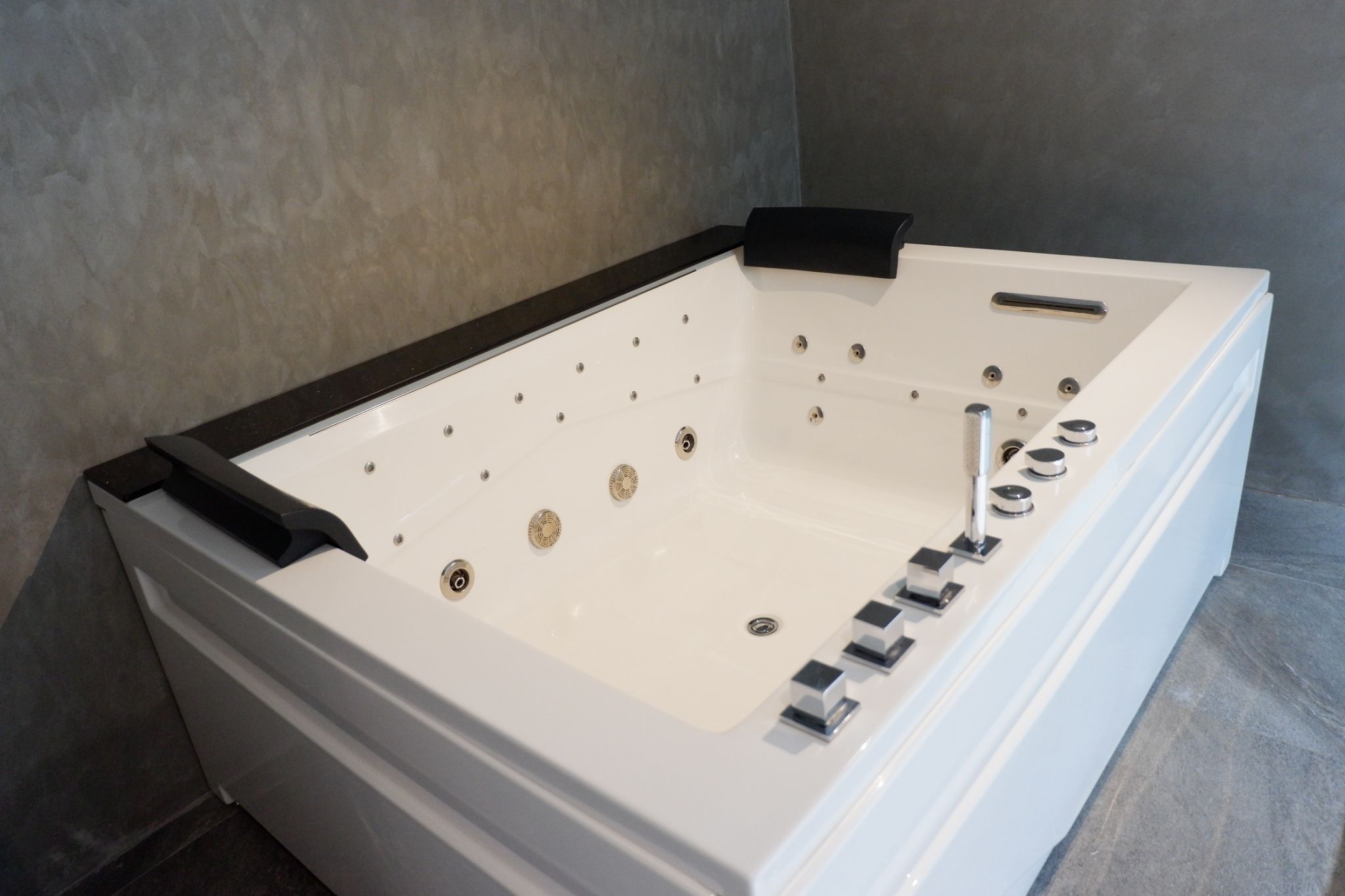 Un bain à remous blanc avec des bordures noires, plusieurs jets et un panneau de commande.