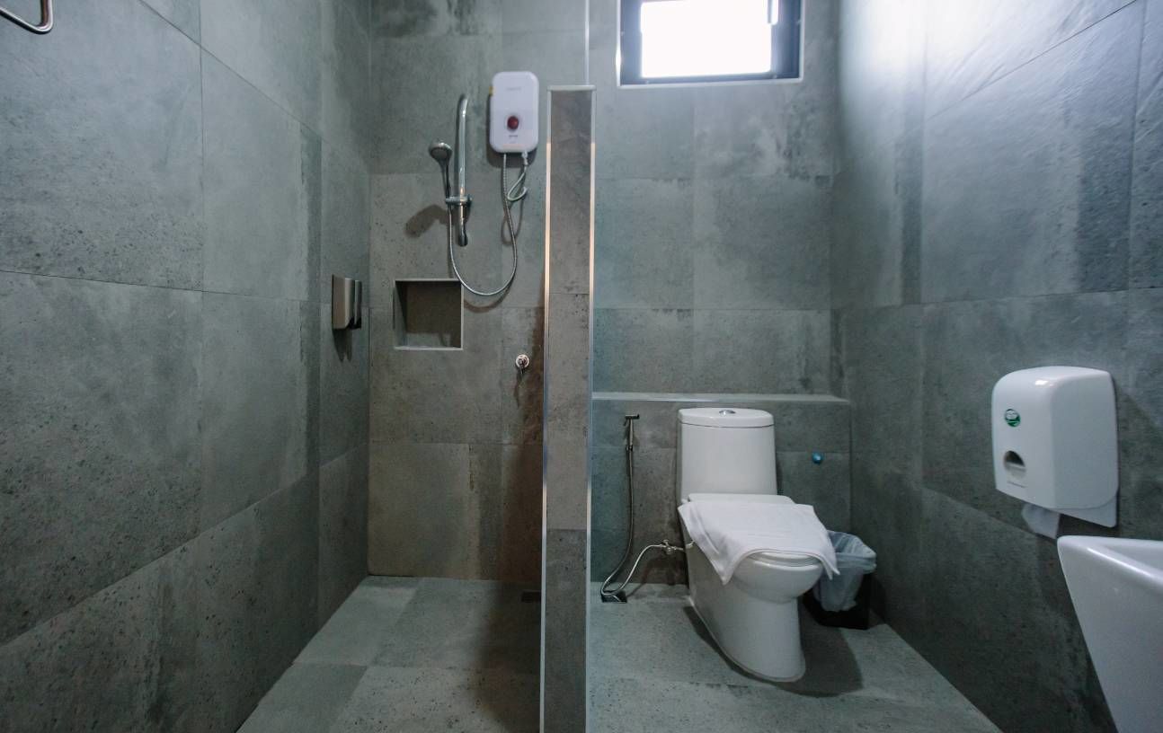 Baño con ducha, inodoro y secamanos.