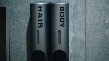 Two metallic dispensers labeled "HAIR" and "BODY" on a textured wall.