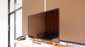 A modern office desk with a flat-screen monitor, a telephone, and a remote control. - Chill D Resort (Buriram)