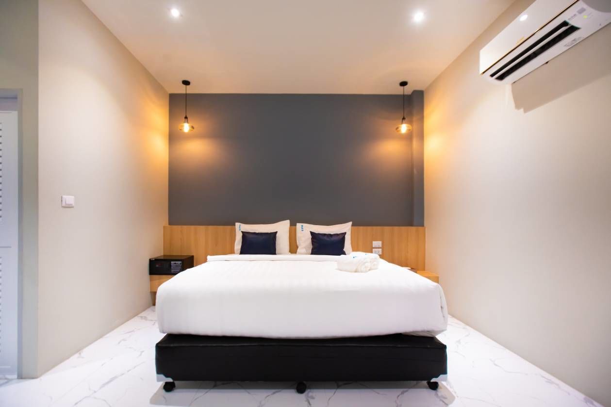 Een moderne hotelkamer met een groot bed, een houten hoofdeinde en twee bedlampjes.