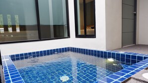 A modern bathroom with a blue-tiled bathtub, a glass shower enclosure, and a white sink. - Chill D Resort (Buriram)