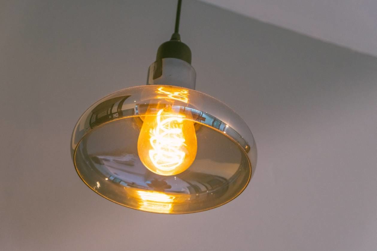 A pendant light with a clear glass shade and an exposed filament bulb.