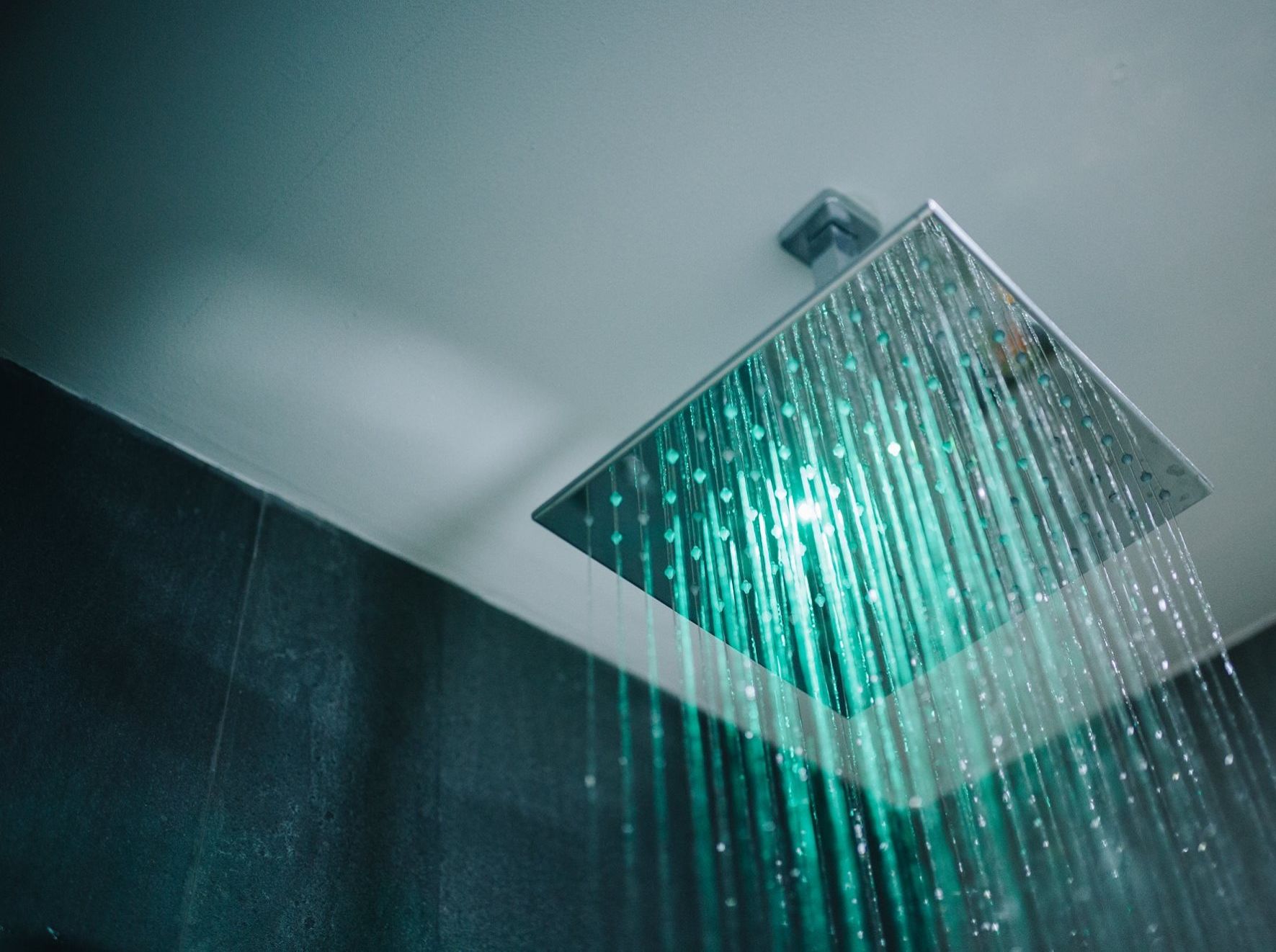 Een moderne douche met een transparant regenpaneel en zichtbare waterstroom.