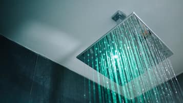 Um chuveiro moderno com um painel de chuva transparente e fluxo de água visível.