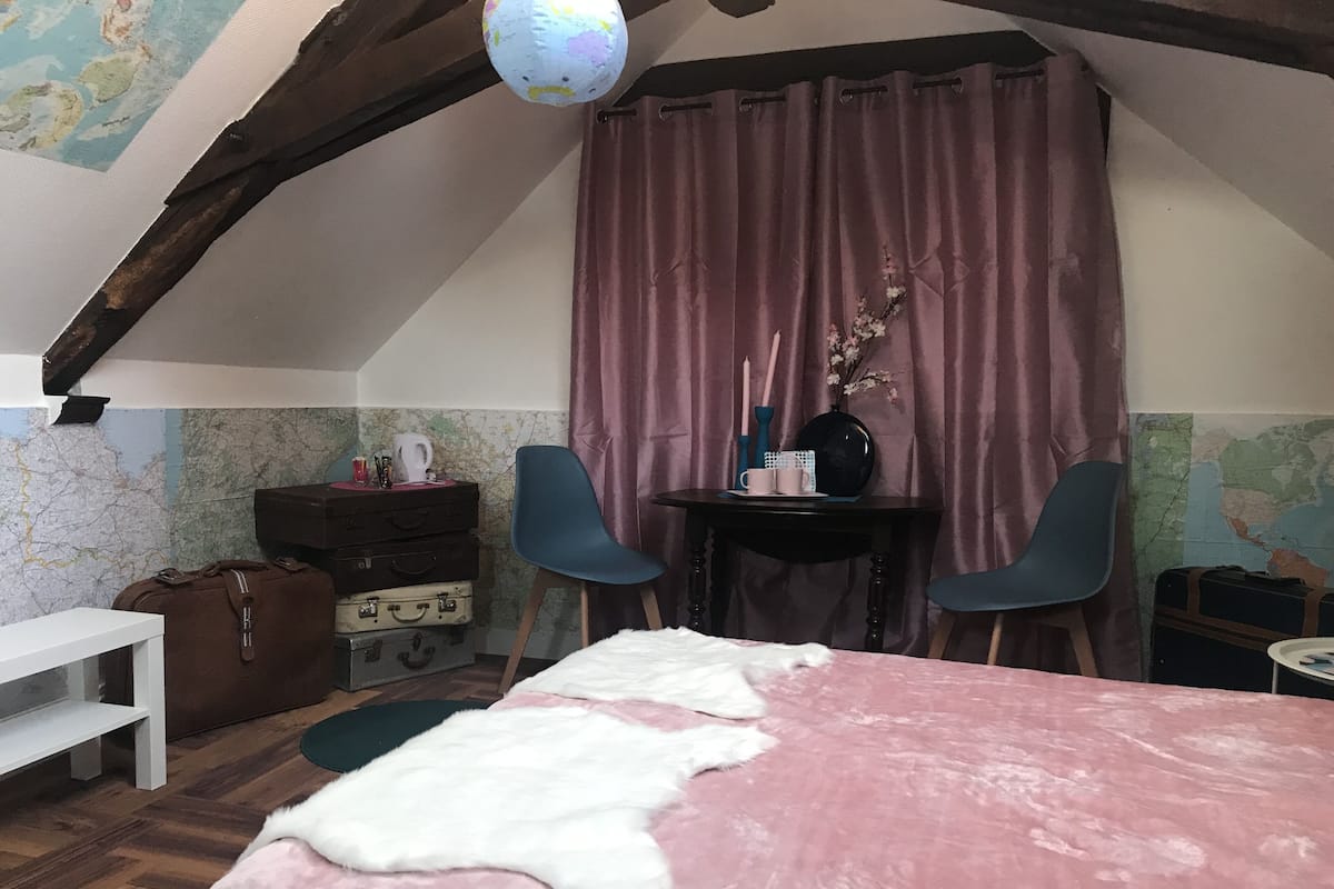 Una habitación acogedora con una cama, un escritorio, dos sillas, una mesa y un mapa en la pared.