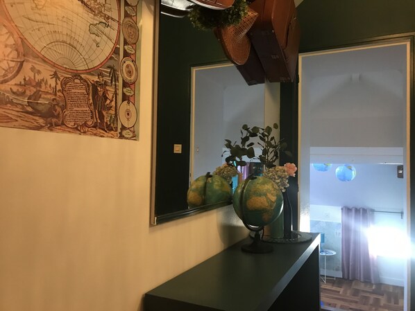 Una habitación con un espejo grande que refleja un globo terráqueo y un mapa en la pared.