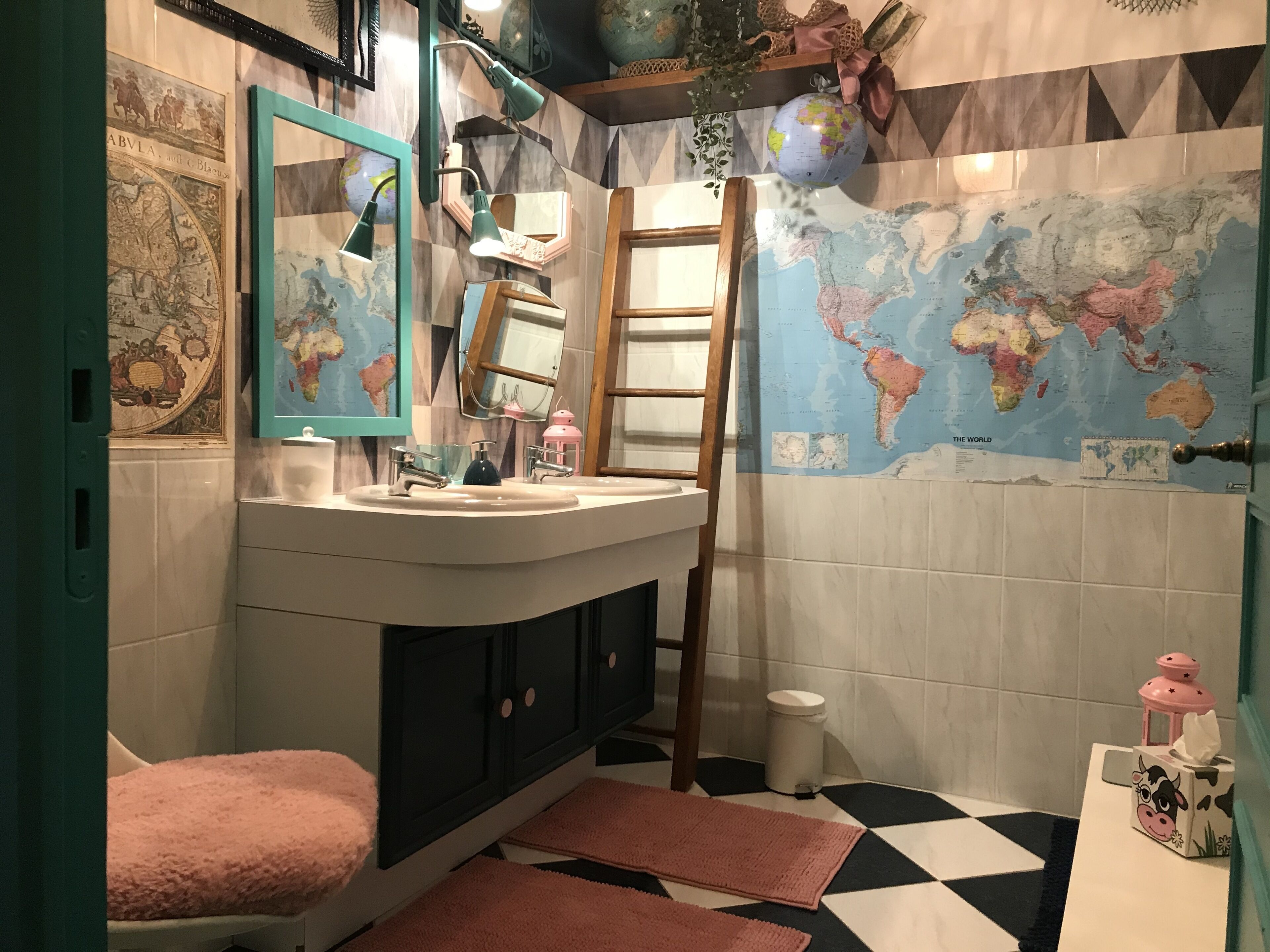Een badkamer met een wastafel, spiegel, wereldbol en handdoekhouder.