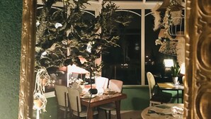 Un comedor con una mesa dispuesta para dos personas, un espejo que refleja la habitación y una araña.