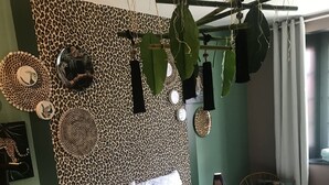Un dormitorio con cabecera de estampado de leopardo, cama con ropa de cama blanca y una planta colgante.