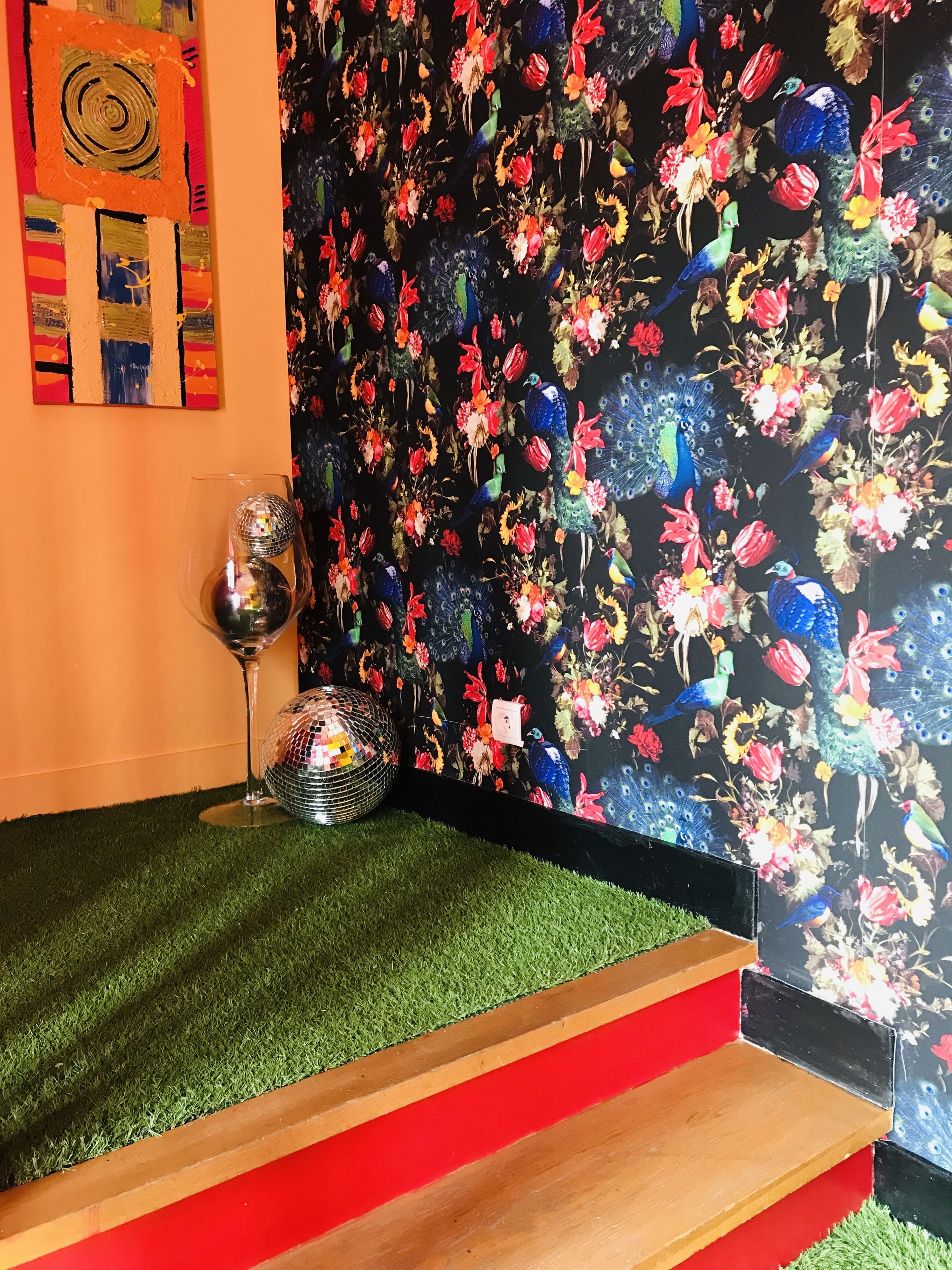 A room with a vibrant floral wallpaper, a disco ball, and a small wooden table.