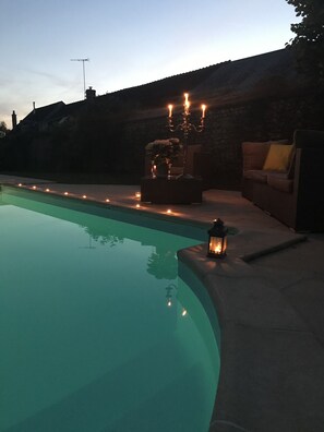 Una piscina con un muro de piedra y un candelabro.