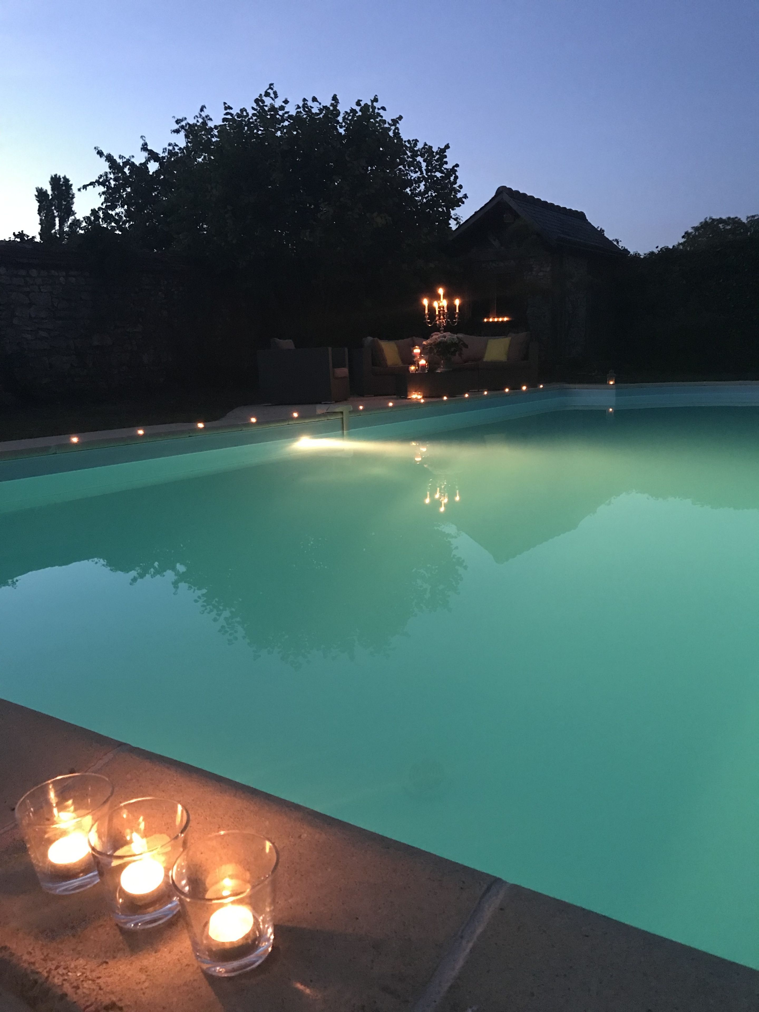 Piscina com borda de pedra, rodeada por um muro baixo e um muro de pedra ao fundo.