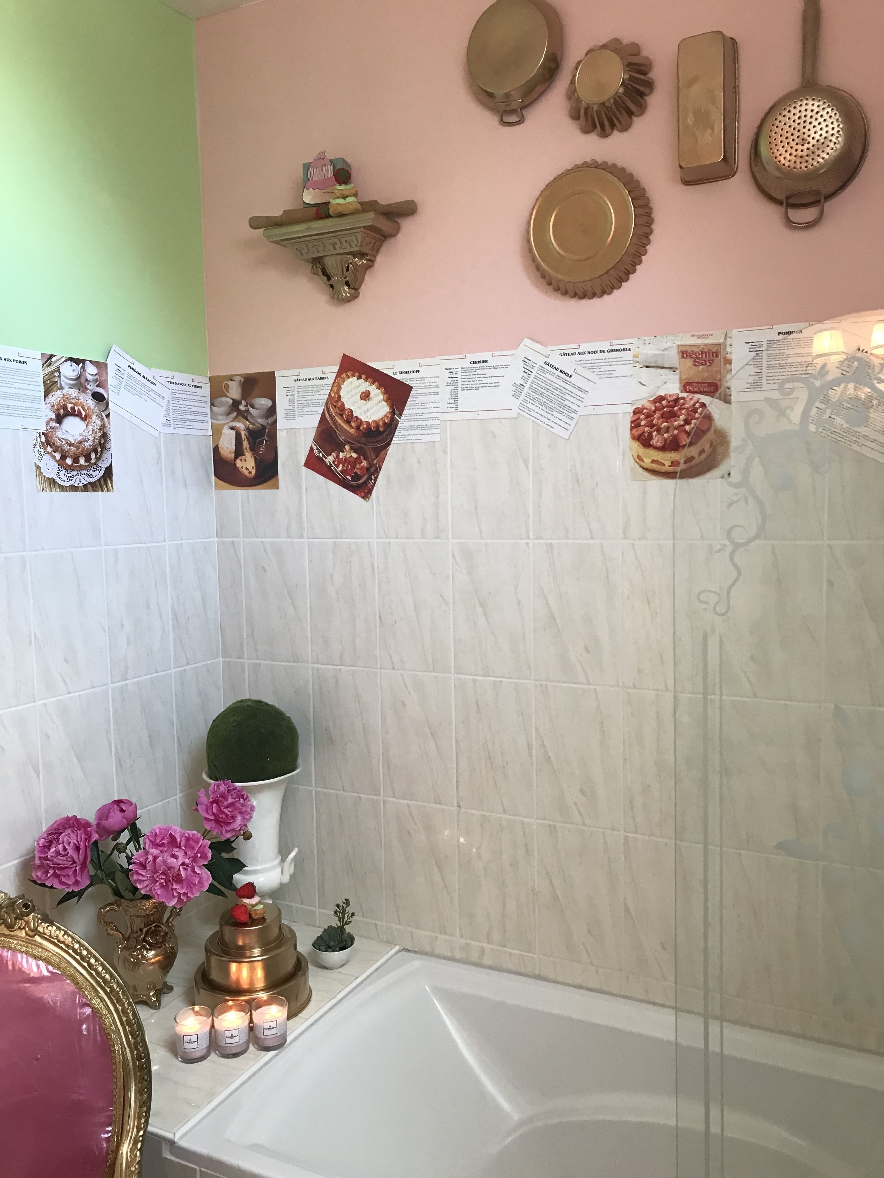 Un baño con bañera, tocador con espejo, un jarrón de flores y un estante con adornos.