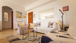 A living room with a sofa, armchair, and coffee table, a wooden door, and a mirror on the wall. - A08 - Magnólia Sea View Apartment by DreamAlgarve (Lagos)