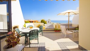 A patio with a table and chairs, a potted plant, and a view of the sea. - A08 - Magnólia Sea View Apartment by DreamAlgarve (Lagos)
