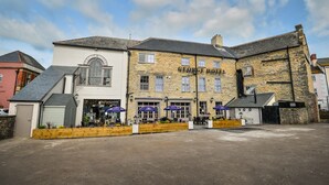 A George Hotel with a stone facade, multiple windows, and outdoor seating with umbrellas. - The George Hotel (Axminster)
