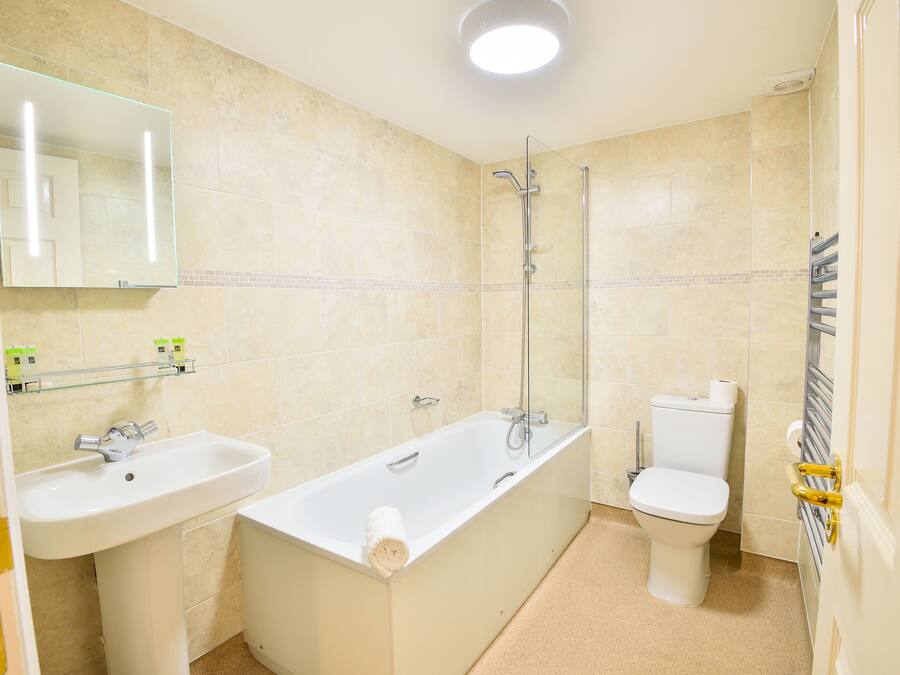 A bathroom with a bathtub, sink, toilet, and a glass shower enclosure.