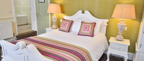 A neatly made bed with a striped bedspread, two bedside lamps, and a white nightstand.