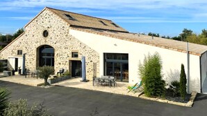 A stone building with a flat roof, large windows, and outdoor seating. - La Petite Félixière, B&B indépendants à 10 min de Cholet, 25 min du Puy du Fou et 35 min de Nantes (Sèvremoine)