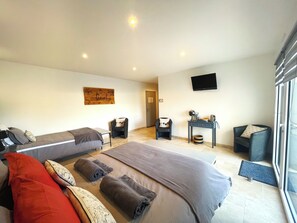 Habitación triple superior, vista al patio | Área de sala de estar | Televisión de pantalla plana, juguetes, libros y oficina 