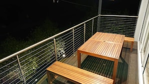 A balcony with a metal railing, a wooden table, and a bench. - Paradise Escapes - 001 (Cowes)