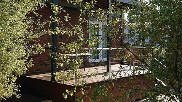 A modern two-story building with a balcony and a brick facade. - Paradise Escapes - 001 (Cowes)