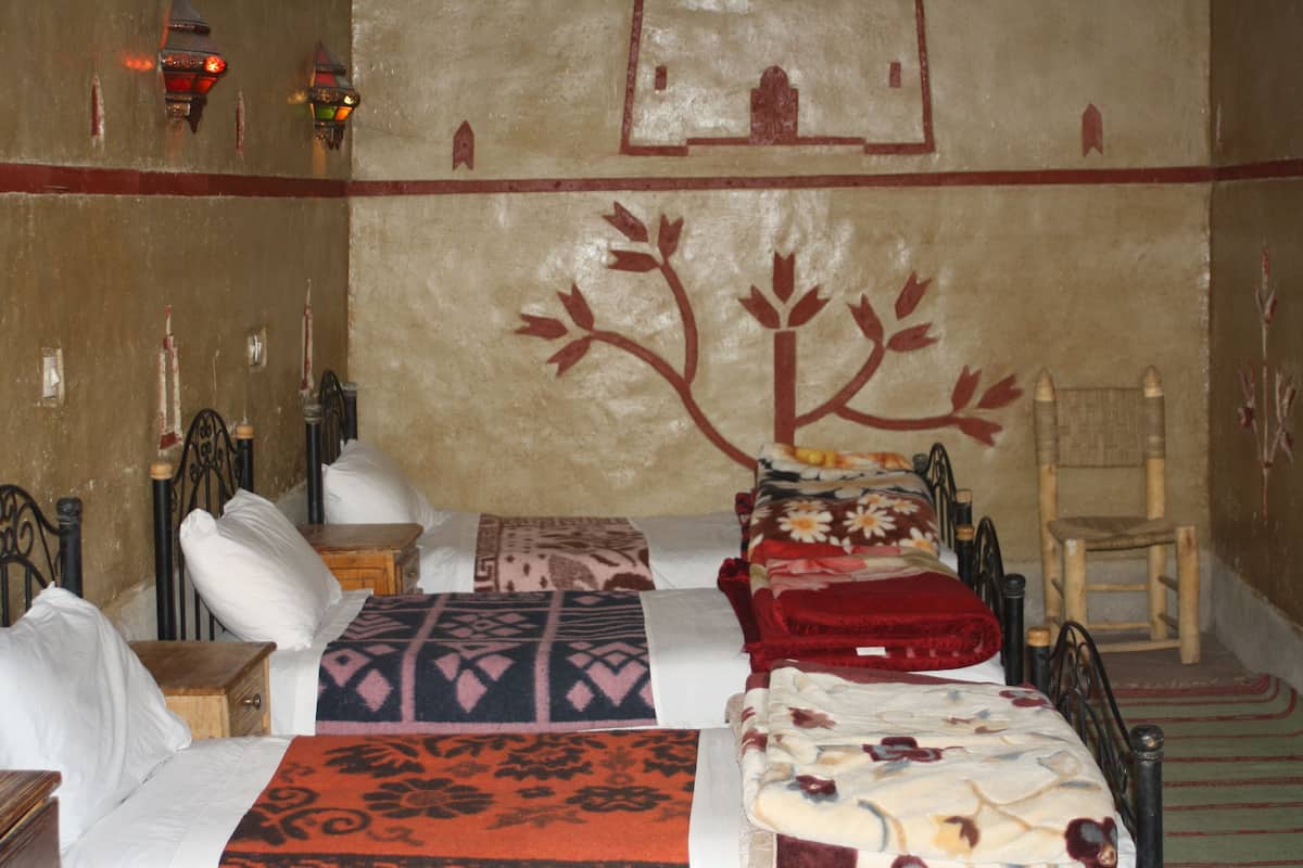 Ein Zimmer mit einem Bett, Kissen, einem Sessel und einer Wand mit Baummotiv.