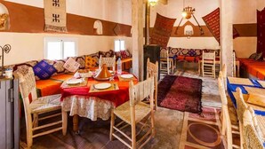Un comedor tradicional con una larga mesa de madera dispuesta para una comida, rodeada de sillas de mimbre.