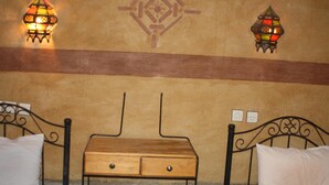 Una habitación con dos camas, una mesita de madera y apliques decorativos en la pared.