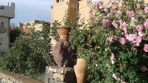 Un muro de piedra con un florero grande y un rosal.