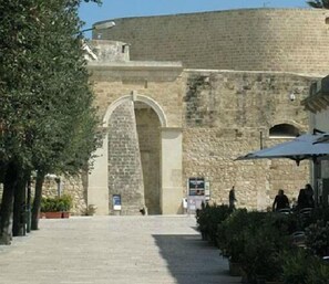 A stone building with an arched entrance, a paved walkway, and some greenery. - Balcone su Otranto (Otranto)