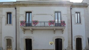 A building with three windows, a balcony with flower boxes, and two doors. - Balcone su Otranto (Otranto)