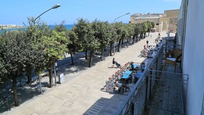 A seaside promenade with outdoor seating, trees, and a clear view of the sea. - Balcone su Otranto (Otranto)