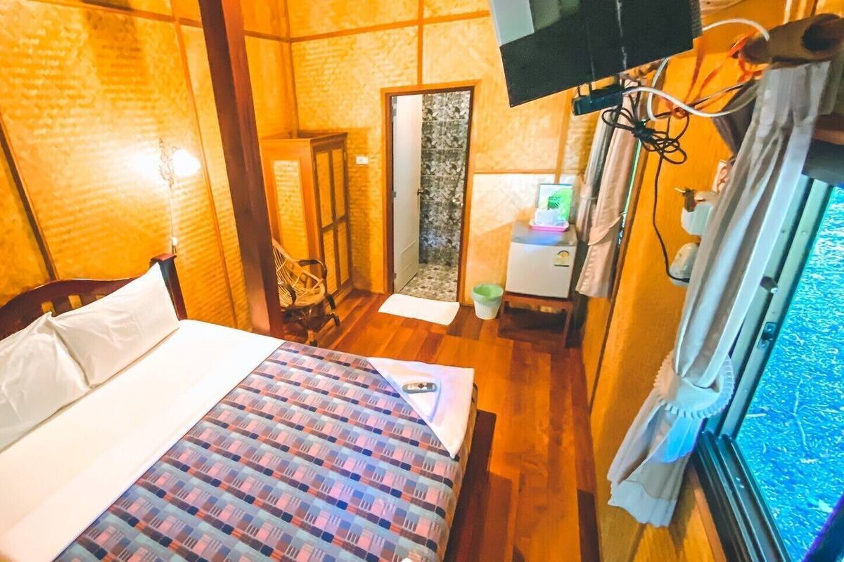 Una habitación con cama, televisión, una mesita y una ventana.