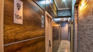 A hallway with wooden paneling and doors numbered 104 and 105. - Level Hotel (Osh)