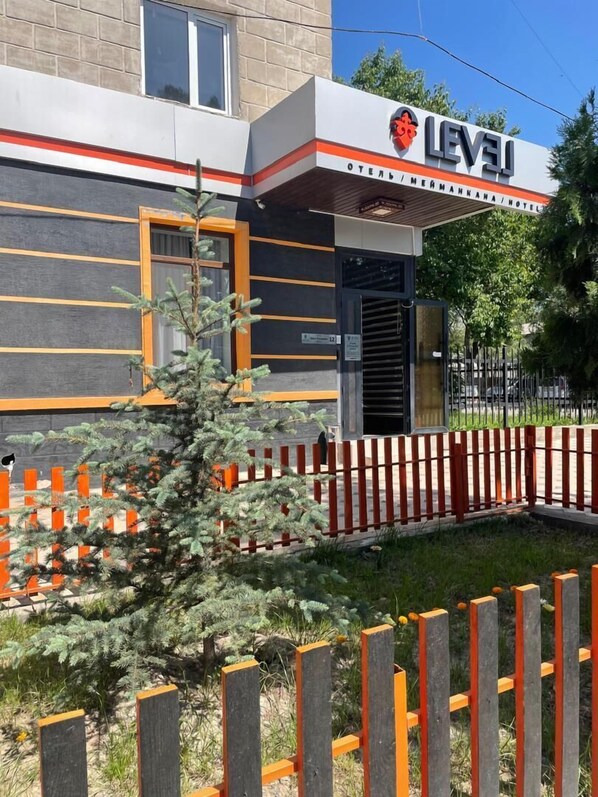 A building with a sign reading "LEVEL HOTEL" and a small tree in front.