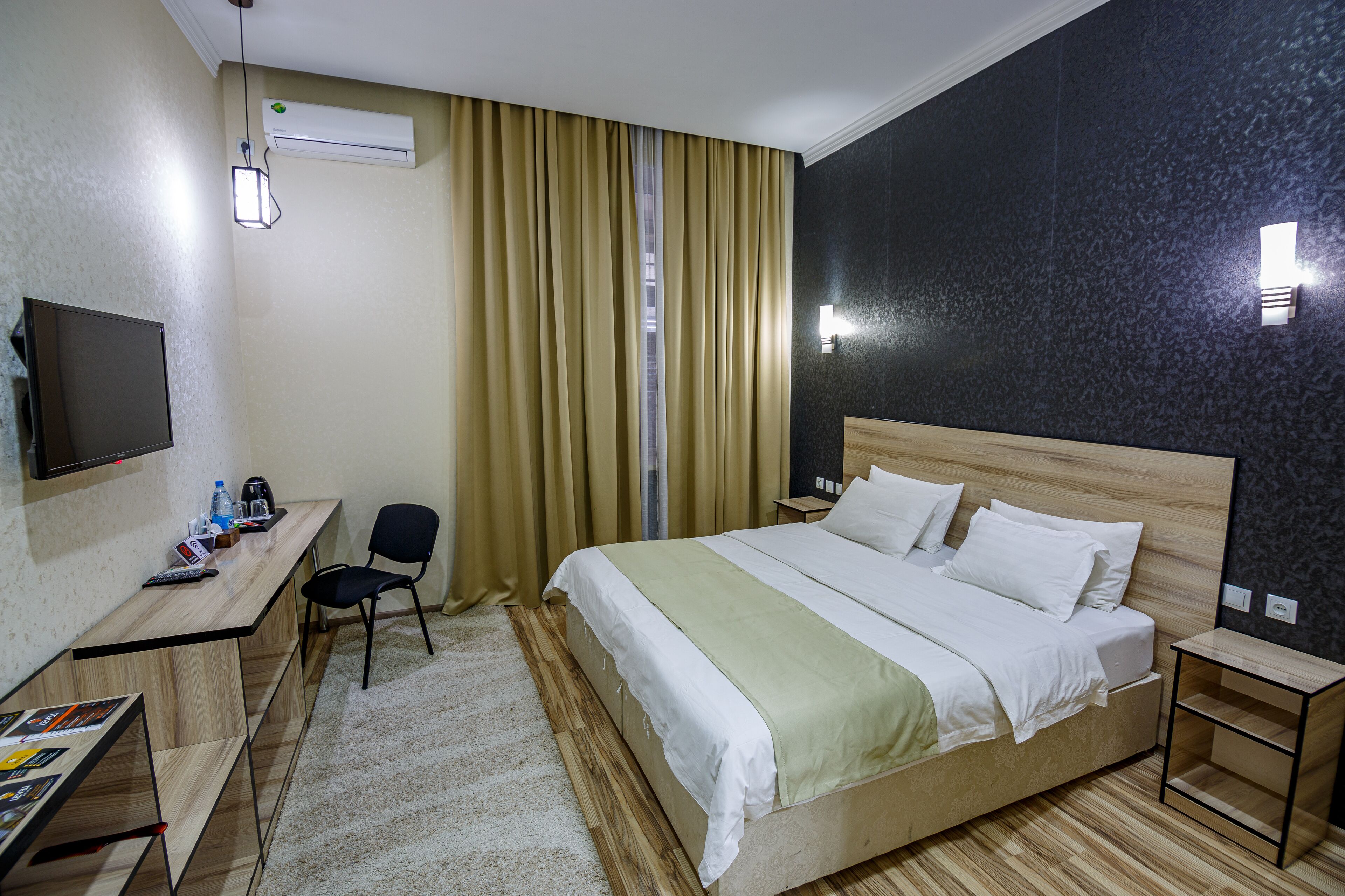 Habitación de hotel con cama, escritorio, silla y televisión en la pared.