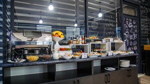 A buffet setup with various food items and beverages. - Level Hotel (Osh)