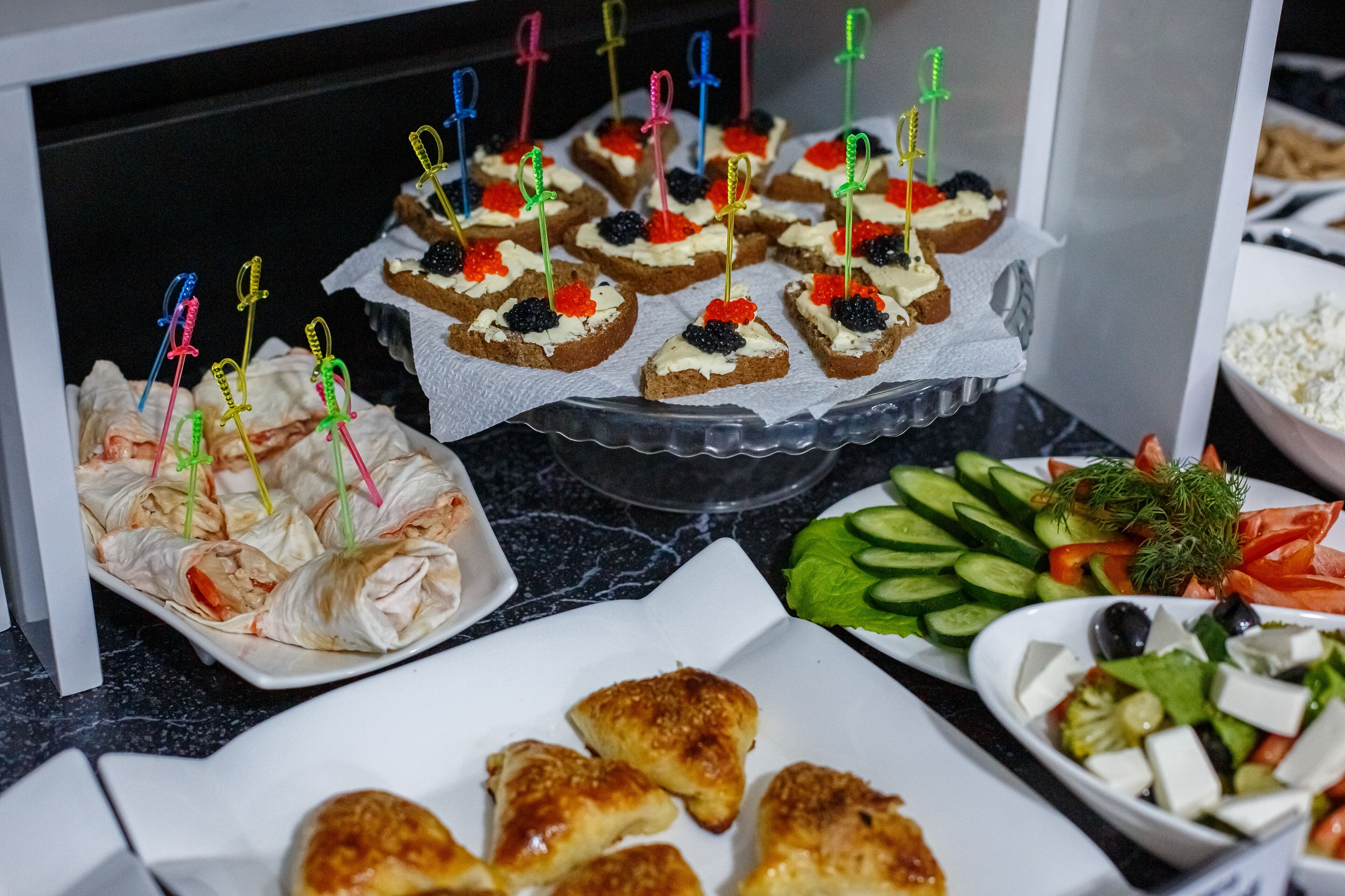 Ein Buffet mit verschiedenen Speisen, darunter Vorspeisen, Salate und Brot.