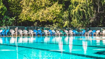 Une piscine bordée de chaises longues bleues et blanches.